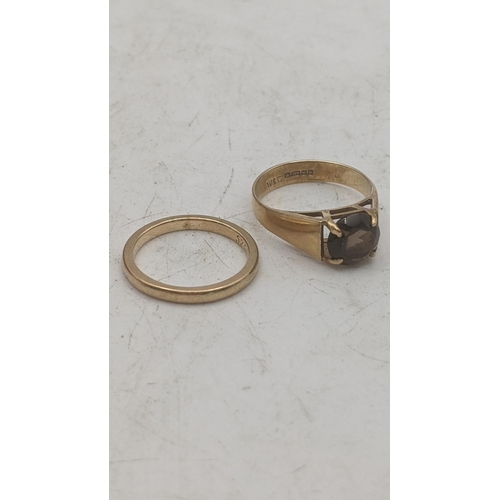 194 - Two 9ct yellow gold ladies rings to include a brilliant cut smoky quartz example, and a wedding band... 