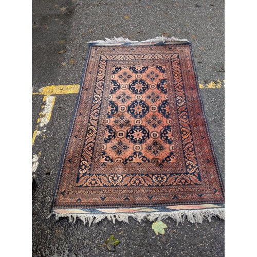 343 - An Afghan rug decorated with three central floral emblems on a red background, 127cm w x 200 cm l A/... 