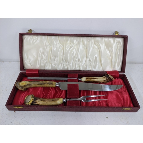 365 - A Sheffield stainless steel horn handled carving set with carving fork, knife and sharpener, in a re... 