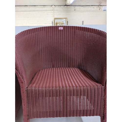 404 - A pink Lloyd Loom tub chair, along with a pink blanket chest with upholstered top raised on tapering... 