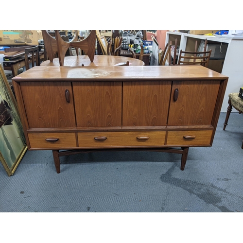 405 - A teak sideboard designed by Victor Wilkins for G-Plan with a pair of folding doors over three drawe... 