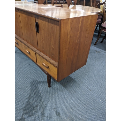 405 - A teak sideboard designed by Victor Wilkins for G-Plan with a pair of folding doors over three drawe... 