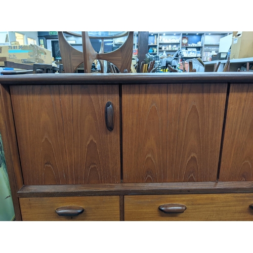 405 - A teak sideboard designed by Victor Wilkins for G-Plan with a pair of folding doors over three drawe... 