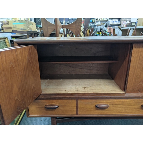 405 - A teak sideboard designed by Victor Wilkins for G-Plan with a pair of folding doors over three drawe... 