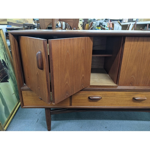 405 - A teak sideboard designed by Victor Wilkins for G-Plan with a pair of folding doors over three drawe... 