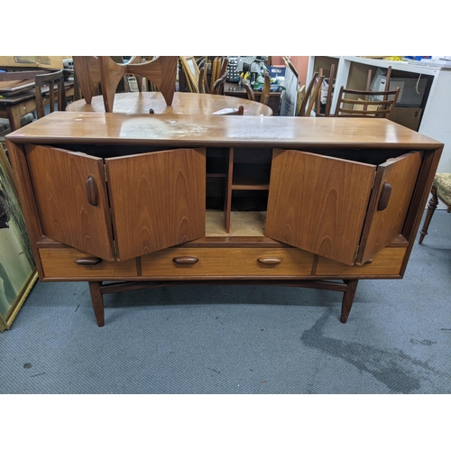 405 - A teak sideboard designed by Victor Wilkins for G-Plan with a pair of folding doors over three drawe... 