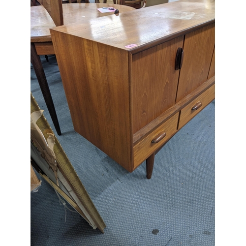 405 - A teak sideboard designed by Victor Wilkins for G-Plan with a pair of folding doors over three drawe... 