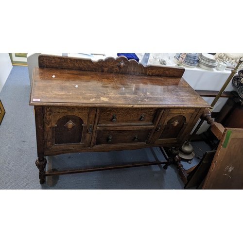 500 - An early 20th century oak sideboard having a raised back and two drawers flanked by cupboard doors, ... 