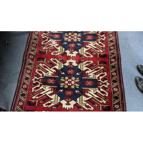 344 - A Persian rug decorated with three central abstract motifs with a red and white repeating border, on... 