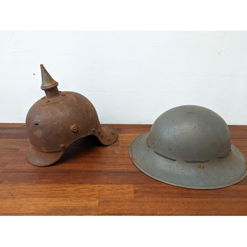 459 - A Prussian helmet stamped Junker 1915, with a leather interior, A/F and a World War II helmet, stamp... 