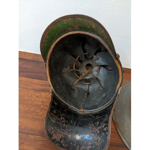 459 - A Prussian helmet stamped Junker 1915, with a leather interior, A/F and a World War II helmet, stamp... 