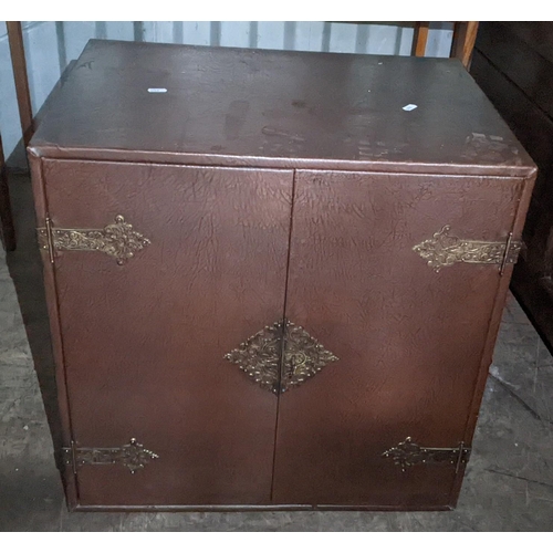 588 - A vintage Korean brown leather two door table top cabinet having cast metal supports and glass shelf... 