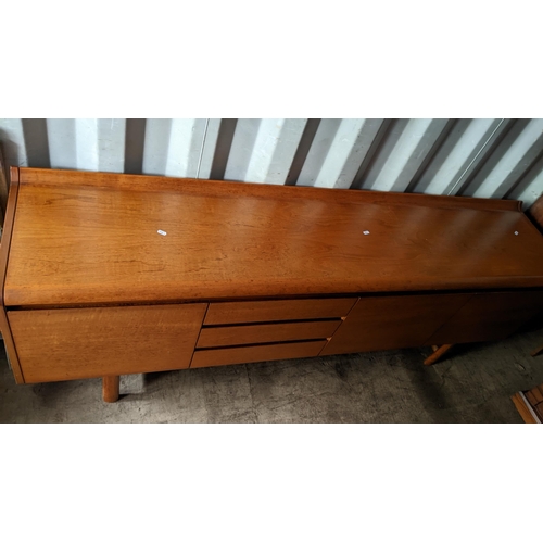 595 - A 1960s White & Newton 'Petersfield' teak sideboard with concave ledge back above an arrangement of ... 