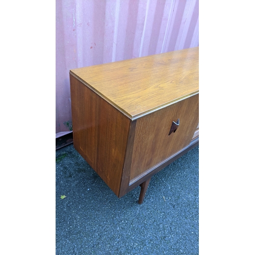 111 - A mid 20th century retro teak sideboard, circa 1960s, having four sliding cupboard doors opening to ... 