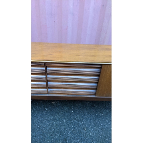 111 - A mid 20th century retro teak sideboard, circa 1960s, having four sliding cupboard doors opening to ... 