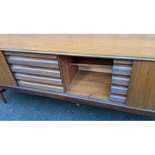 111 - A mid 20th century retro teak sideboard, circa 1960s, having four sliding cupboard doors opening to ... 