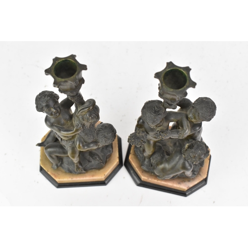 25 - Two 19th century bronze figural candlesticks, each cast with a dolphin and putti holding a cornucopi... 