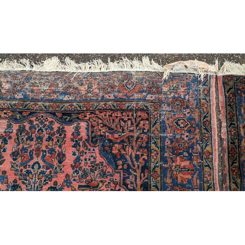 256 - A pair of Persian pictorial hand woven rugs, each on a red ground, the field decorated with an urn, ... 