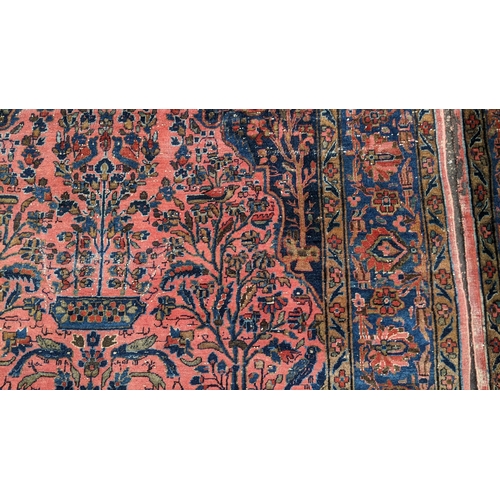 256 - A pair of Persian pictorial hand woven rugs, each on a red ground, the field decorated with an urn, ... 