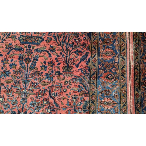 256 - A pair of Persian pictorial hand woven rugs, each on a red ground, the field decorated with an urn, ... 