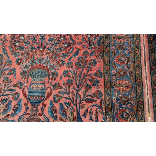 256 - A pair of Persian pictorial hand woven rugs, each on a red ground, the field decorated with an urn, ... 