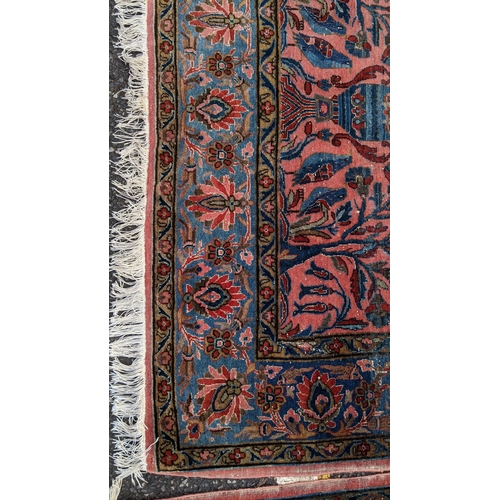 256 - A pair of Persian pictorial hand woven rugs, each on a red ground, the field decorated with an urn, ... 