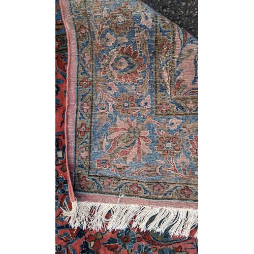 256 - A pair of Persian pictorial hand woven rugs, each on a red ground, the field decorated with an urn, ... 