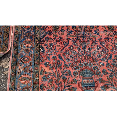 256 - A pair of Persian pictorial hand woven rugs, each on a red ground, the field decorated with an urn, ... 