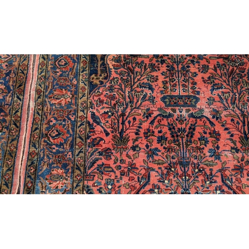 256 - A pair of Persian pictorial hand woven rugs, each on a red ground, the field decorated with an urn, ... 