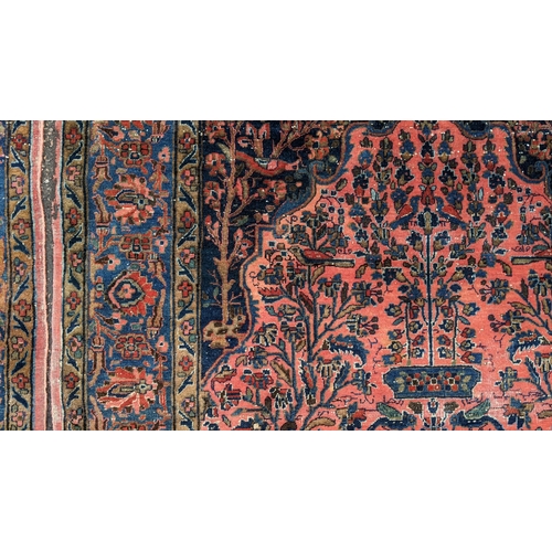 256 - A pair of Persian pictorial hand woven rugs, each on a red ground, the field decorated with an urn, ... 