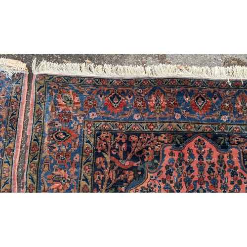 256 - A pair of Persian pictorial hand woven rugs, each on a red ground, the field decorated with an urn, ... 