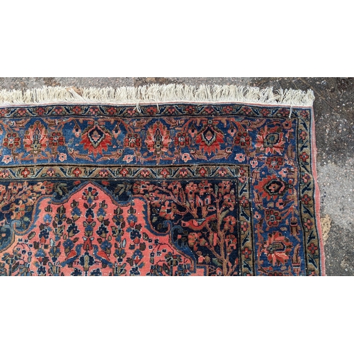 256 - A pair of Persian pictorial hand woven rugs, each on a red ground, the field decorated with an urn, ... 