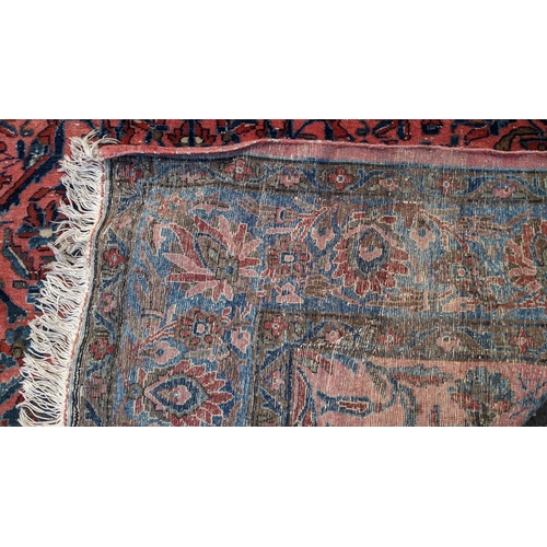 256 - A pair of Persian pictorial hand woven rugs, each on a red ground, the field decorated with an urn, ... 