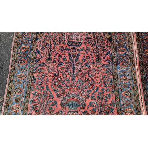 256 - A pair of Persian pictorial hand woven rugs, each on a red ground, the field decorated with an urn, ... 