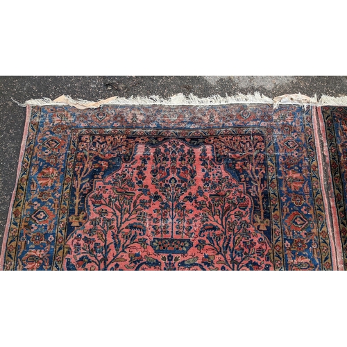 256 - A pair of Persian pictorial hand woven rugs, each on a red ground, the field decorated with an urn, ... 