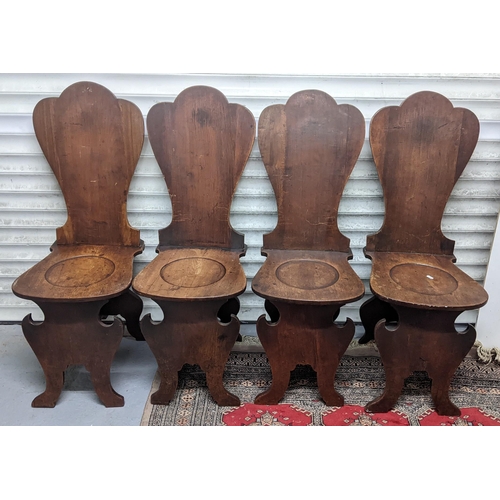 263 - A set of four George II mahogany hall chairs, each of sgabello form with escutcheon shaped backs, ci... 