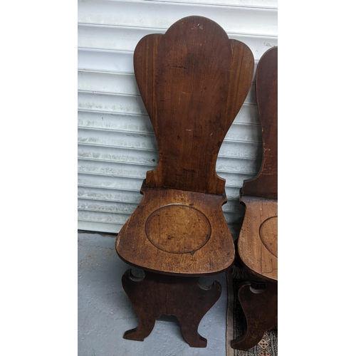 263 - A set of four George II mahogany hall chairs, each of sgabello form with escutcheon shaped backs, ci... 