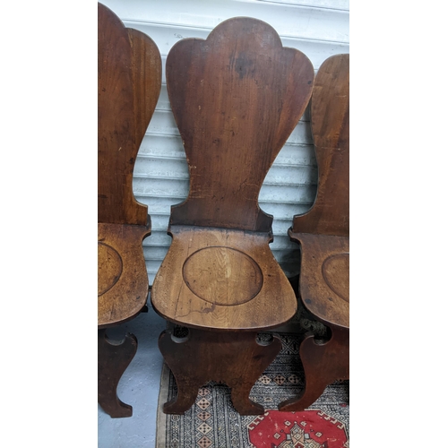 263 - A set of four George II mahogany hall chairs, each of sgabello form with escutcheon shaped backs, ci... 