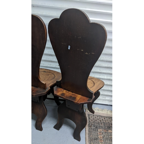 263 - A set of four George II mahogany hall chairs, each of sgabello form with escutcheon shaped backs, ci... 