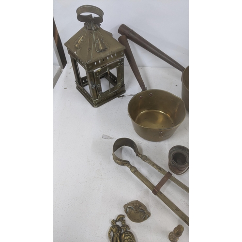 111 - A mixed lot of brass wear to include two saucepans, fine side dogs, fine side items, a lantern, bell... 