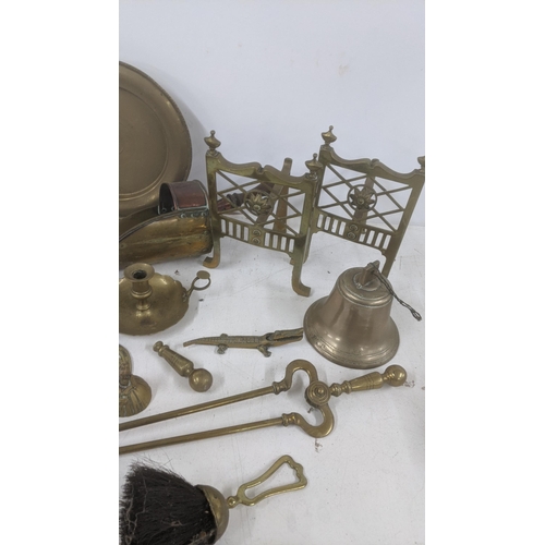 111 - A mixed lot of brass wear to include two saucepans, fine side dogs, fine side items, a lantern, bell... 