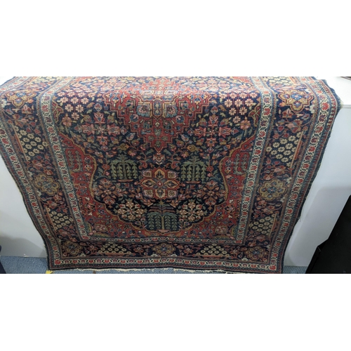 14 - A Middle Eastern Kirman hand woven rug having a floral design on a red field with multi-guard boarde... 