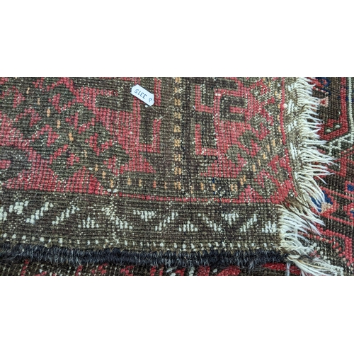 15 - A Persian hand woven red ground rug having geometric designs and tasselled ends, 224cm x 123cm w
Loc... 