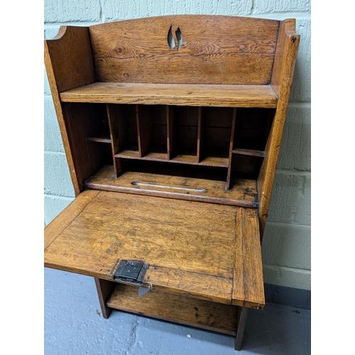 62A - An Arts and Crafts oak student bureau with a pierced gallery, with a fall front enclosing fitted int... 