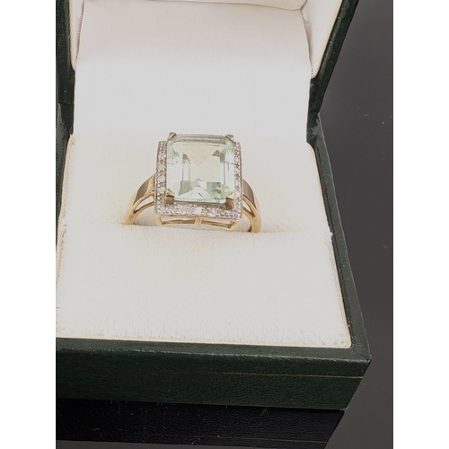 74C - A 9ct gold ring set with an emerald cut aquamarine, 3.6ct, within a border of fourteen diamonds, 3.2... 