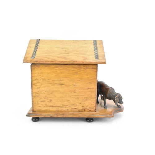 159 - An early 20th century oak novelty cigar and music box, in the form of a kennel with patinated metal ... 