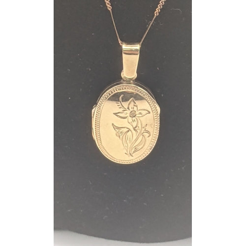 1 - A yellow gold and oval shaped floral engraved locket pendant tested as 14ct gold on a 14ct yellow go... 