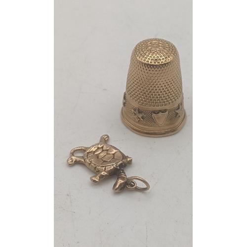 10 - An yellow metal thimble tested as 14ct gold 4.4g together with a 9ct yellow gold charm fashioned as ... 