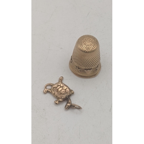 10 - An yellow metal thimble tested as 14ct gold 4.4g together with a 9ct yellow gold charm fashioned as ... 