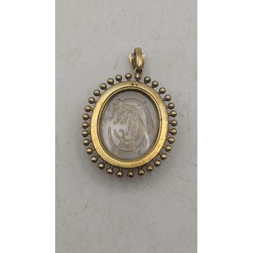 11 - An Victorian possibly rock crystal oval shaped pendant with engraved initials mounted in a yellow go... 